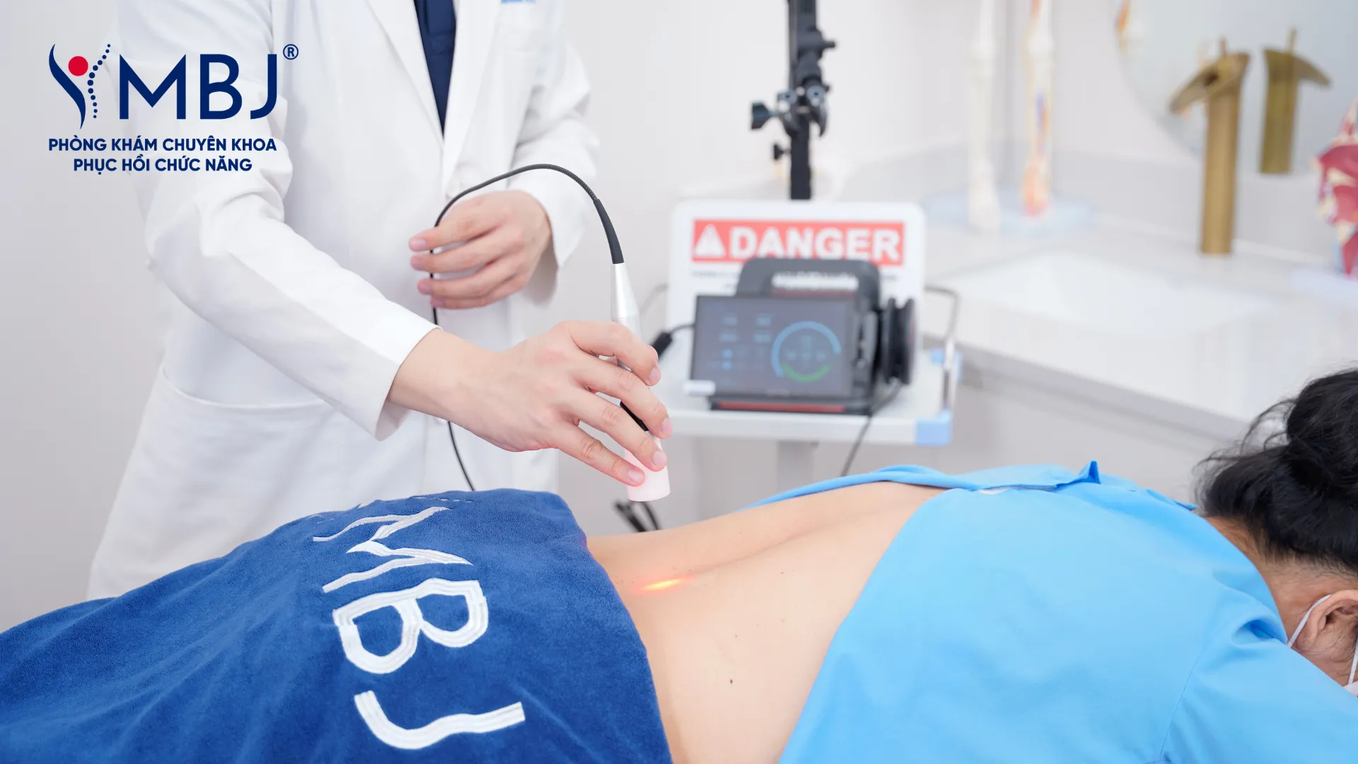 Máy laser Class IV chiếu ánh sáng đỏ vào vùng lưng bệnh nhân tại phòng khám MBJ