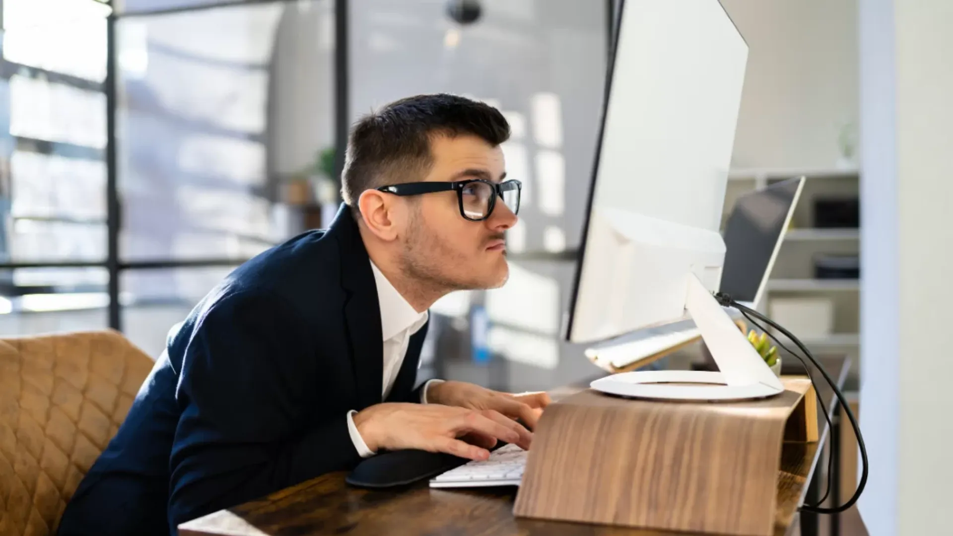 Người trẻ cúi cổ làm việc với laptop đặt thấp gây tăng tải lên cột sống cổ